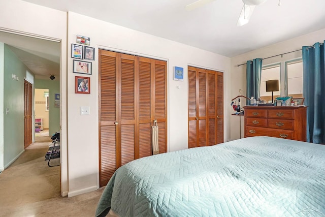 bedroom with multiple closets, light carpet, and ceiling fan