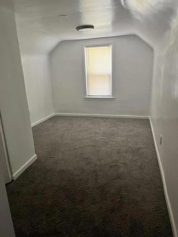 additional living space with lofted ceiling and dark colored carpet