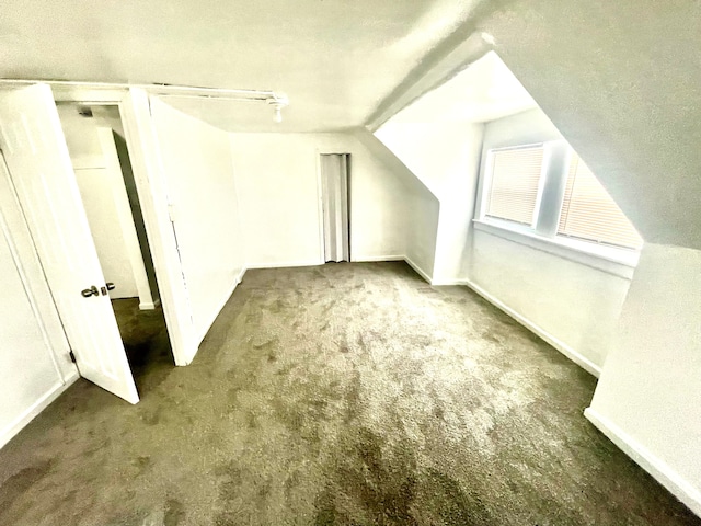 bonus room with dark carpet and vaulted ceiling