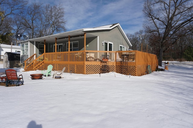 snow covered rear of property featuring a deck and an outdoor fire pit