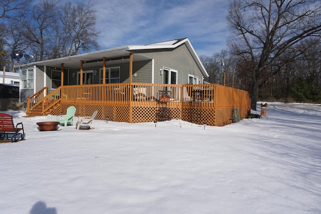 snow covered back of property with a wooden deck