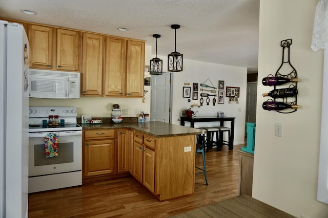 kitchen with pendant lighting, white appliances, a breakfast bar area, dark hardwood / wood-style floors, and kitchen peninsula