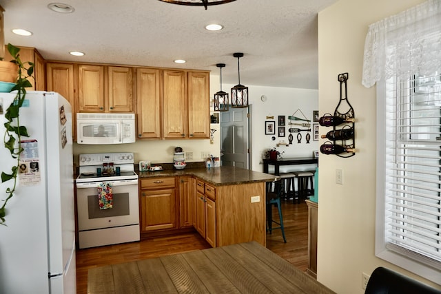 kitchen with decorative light fixtures, dark wood-type flooring, white appliances, and kitchen peninsula