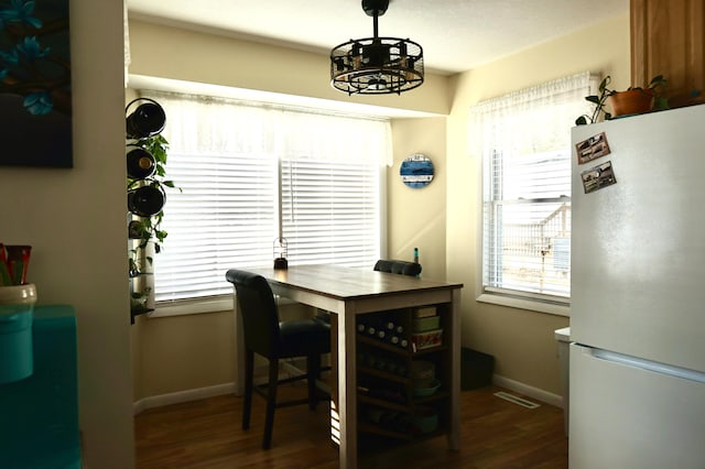 dining area featuring a notable chandelier, dark hardwood / wood-style floors, and a healthy amount of sunlight