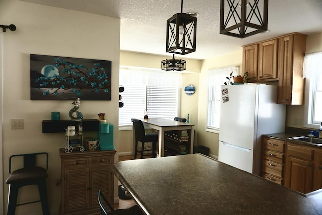 kitchen featuring hanging light fixtures, white fridge, a healthy amount of sunlight, and a textured ceiling