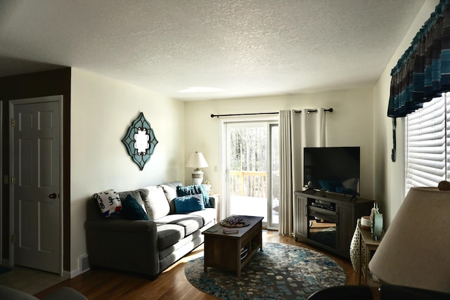 living room with dark wood-type flooring and a textured ceiling