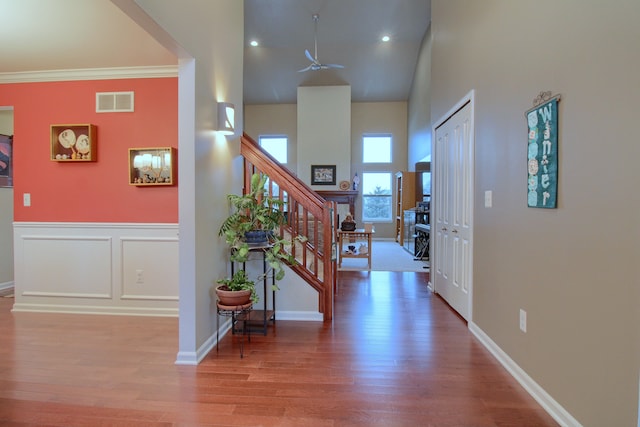 entrance foyer featuring crown molding, a towering ceiling, ceiling fan, and light hardwood / wood-style floors