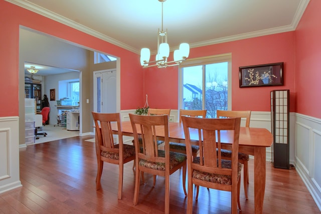 dining space with ornamental molding, a healthy amount of sunlight, hardwood / wood-style floors, and a notable chandelier