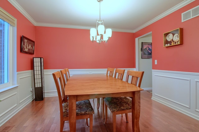 dining area with crown molding, a healthy amount of sunlight, a notable chandelier, and light wood-type flooring