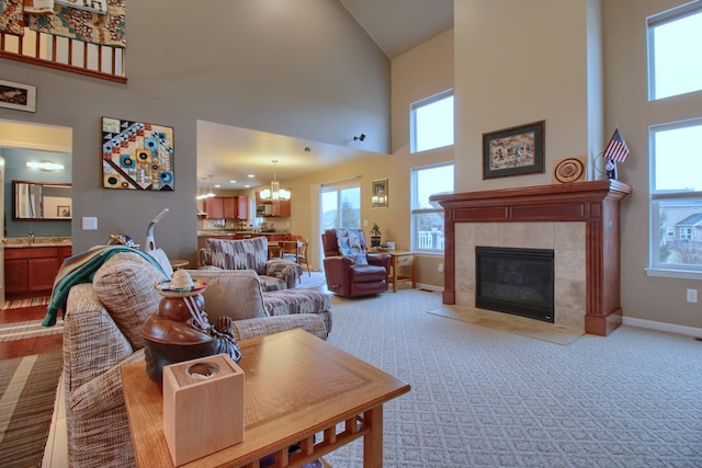 carpeted living room with a tiled fireplace, a notable chandelier, and a high ceiling