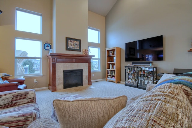 living room with a tile fireplace, carpet floors, and high vaulted ceiling