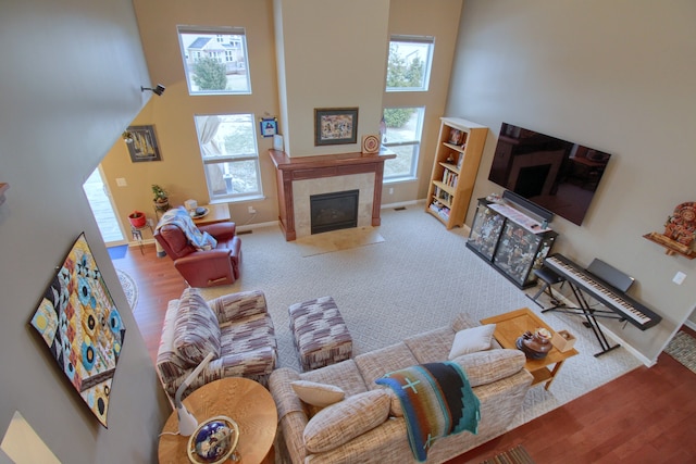 living room with a towering ceiling, plenty of natural light, and a tiled fireplace