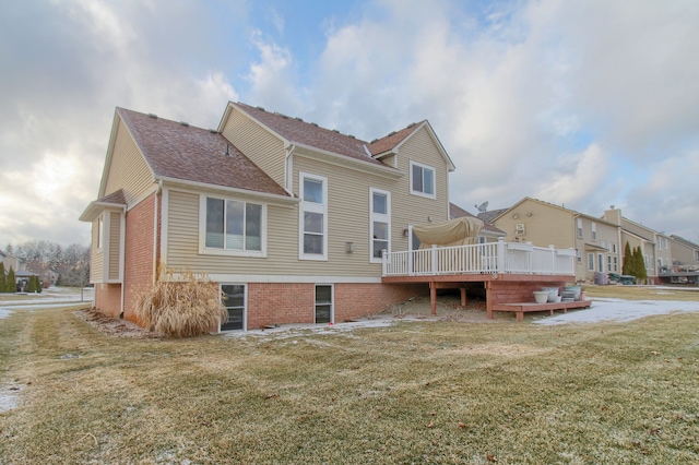 rear view of house with a wooden deck and a lawn