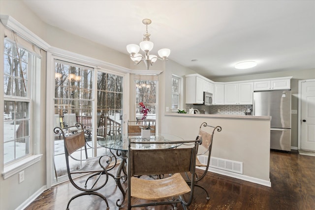 dining room featuring dark wood-type flooring, a wealth of natural light, and a chandelier