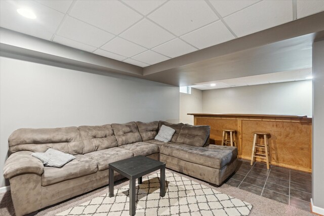 living room featuring a drop ceiling and dark tile patterned flooring