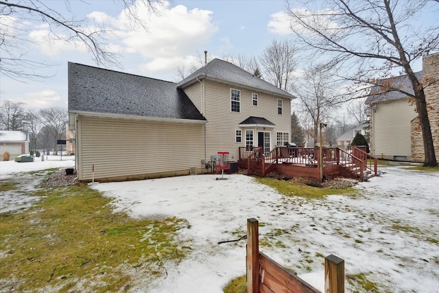 snow covered back of property featuring a deck