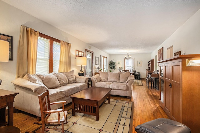 living room with a textured ceiling, a chandelier, and light hardwood / wood-style floors