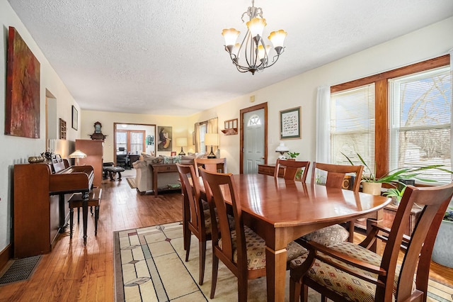 dining room featuring wood-type flooring, a chandelier, and a textured ceiling