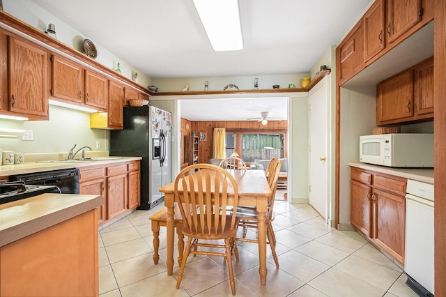 kitchen featuring sink, wood walls, stainless steel fridge with ice dispenser, black dishwasher, and ceiling fan