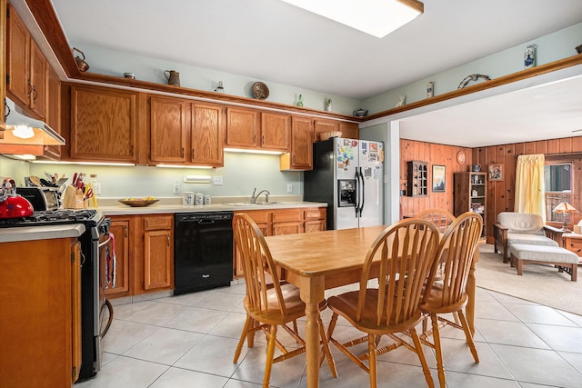 kitchen featuring light tile patterned flooring, appliances with stainless steel finishes, sink, and wooden walls