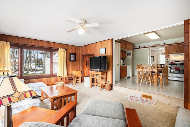 living room with ceiling fan, light colored carpet, and wooden walls