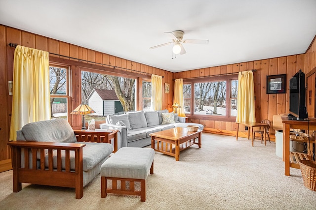 carpeted living room featuring ceiling fan and wooden walls