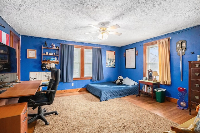 bedroom featuring ceiling fan, hardwood / wood-style floors, and a textured ceiling