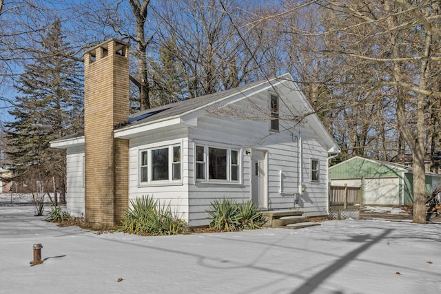 view of snow covered exterior featuring a garage and an outbuilding