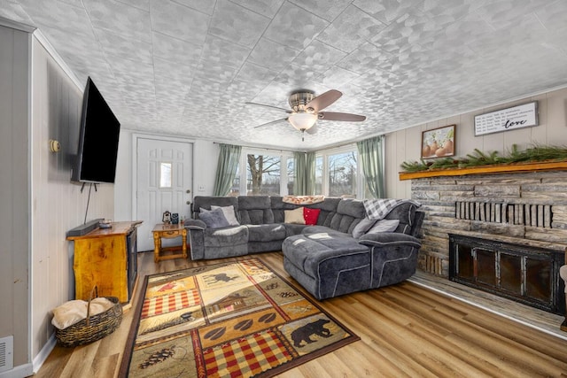 living room featuring ceiling fan, a fireplace, and light hardwood / wood-style floors