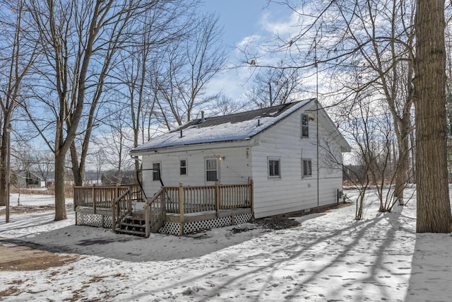 snow covered house with a wooden deck