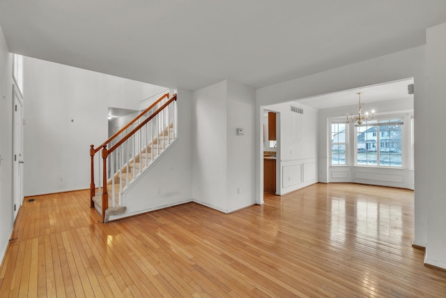 unfurnished living room with a chandelier and light wood-type flooring