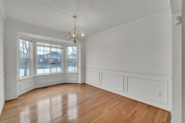 unfurnished dining area featuring ornamental molding, a chandelier, and light hardwood / wood-style floors