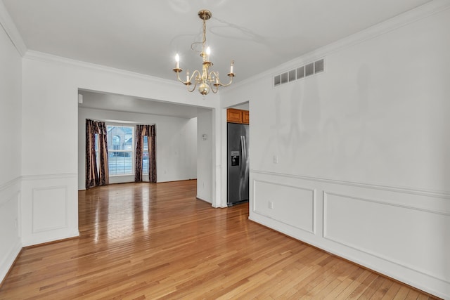 unfurnished dining area with crown molding, a chandelier, and light hardwood / wood-style floors