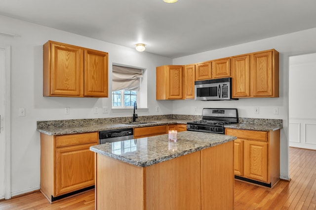 kitchen with light stone counters, stainless steel appliances, sink, and a kitchen island