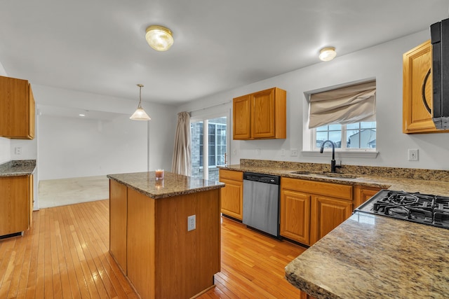 kitchen featuring sink, light wood-type flooring, dishwasher, a kitchen island, and pendant lighting