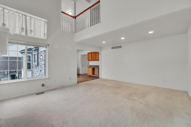 unfurnished living room featuring a high ceiling and carpet flooring