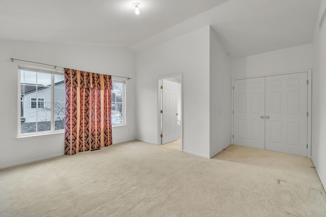 unfurnished bedroom featuring a closet, lofted ceiling, and light carpet