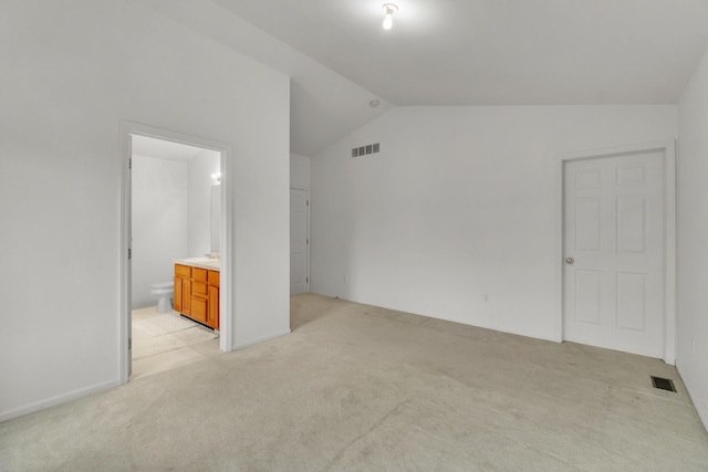 interior space with vaulted ceiling, light carpet, and ensuite bathroom