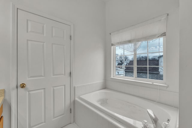 bathroom featuring vanity and tiled bath