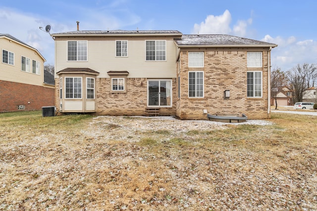 rear view of property featuring central AC and a lawn