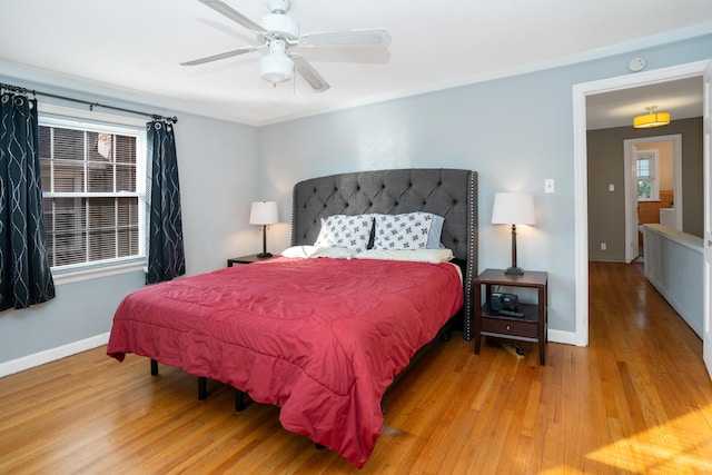 bedroom featuring ceiling fan, multiple windows, and light hardwood / wood-style flooring