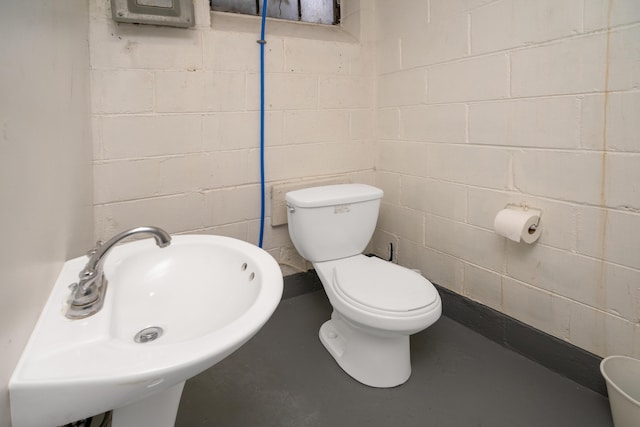 bathroom with toilet, sink, and concrete floors