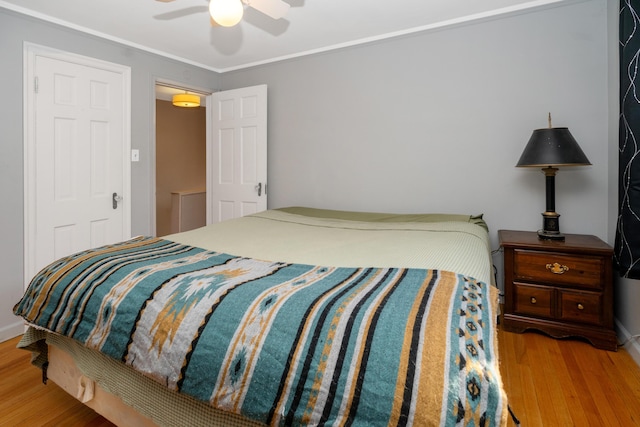 bedroom with hardwood / wood-style floors, ornamental molding, and ceiling fan