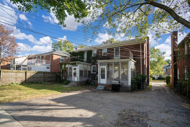 back of house featuring a lawn and a sunroom