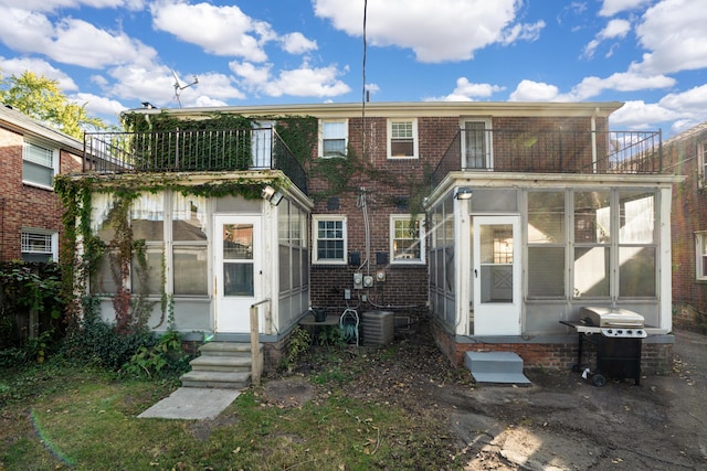 rear view of property with a balcony, a sunroom, and central air condition unit