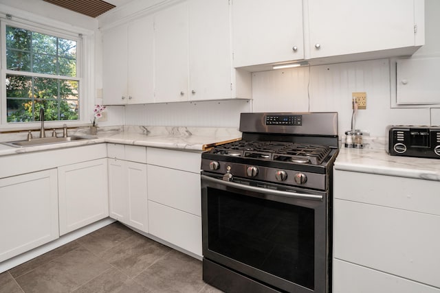 kitchen with stainless steel range with gas stovetop, sink, and white cabinets