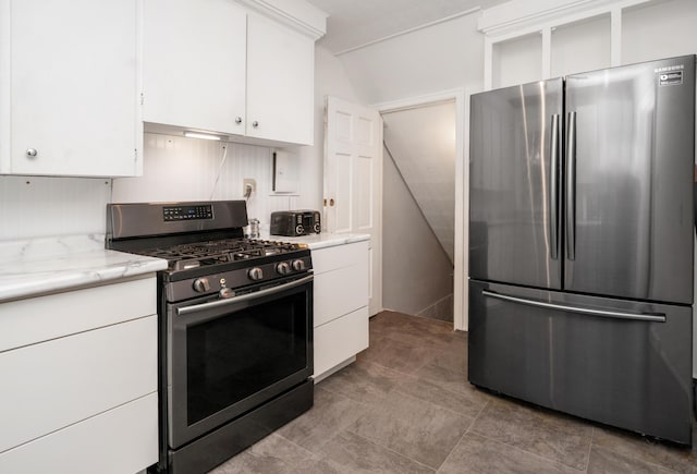 kitchen with stainless steel appliances, vaulted ceiling, white cabinets, and light stone counters