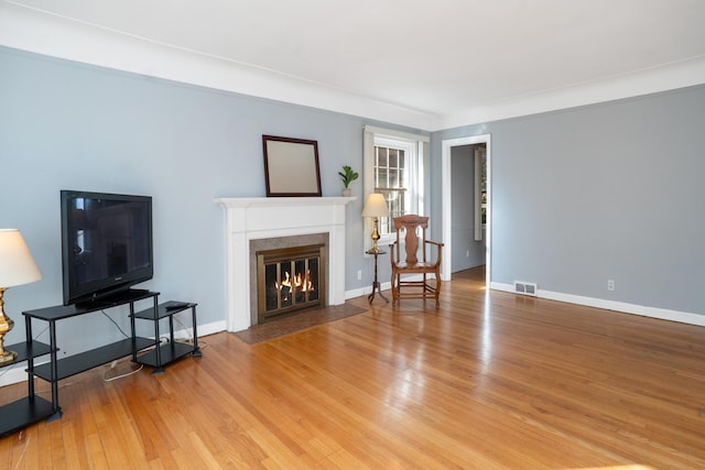 living room with a high end fireplace and hardwood / wood-style floors