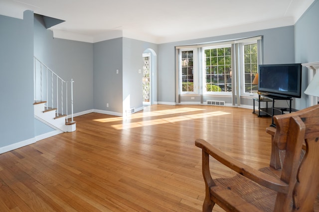 unfurnished living room featuring crown molding and light hardwood / wood-style floors