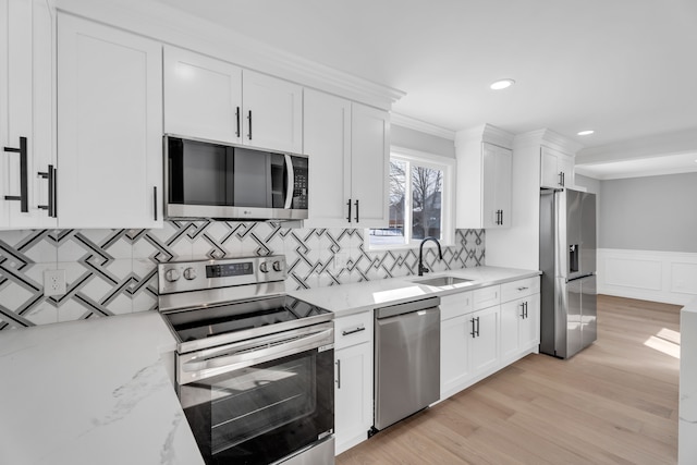 kitchen with stainless steel appliances, white cabinetry, and light stone counters